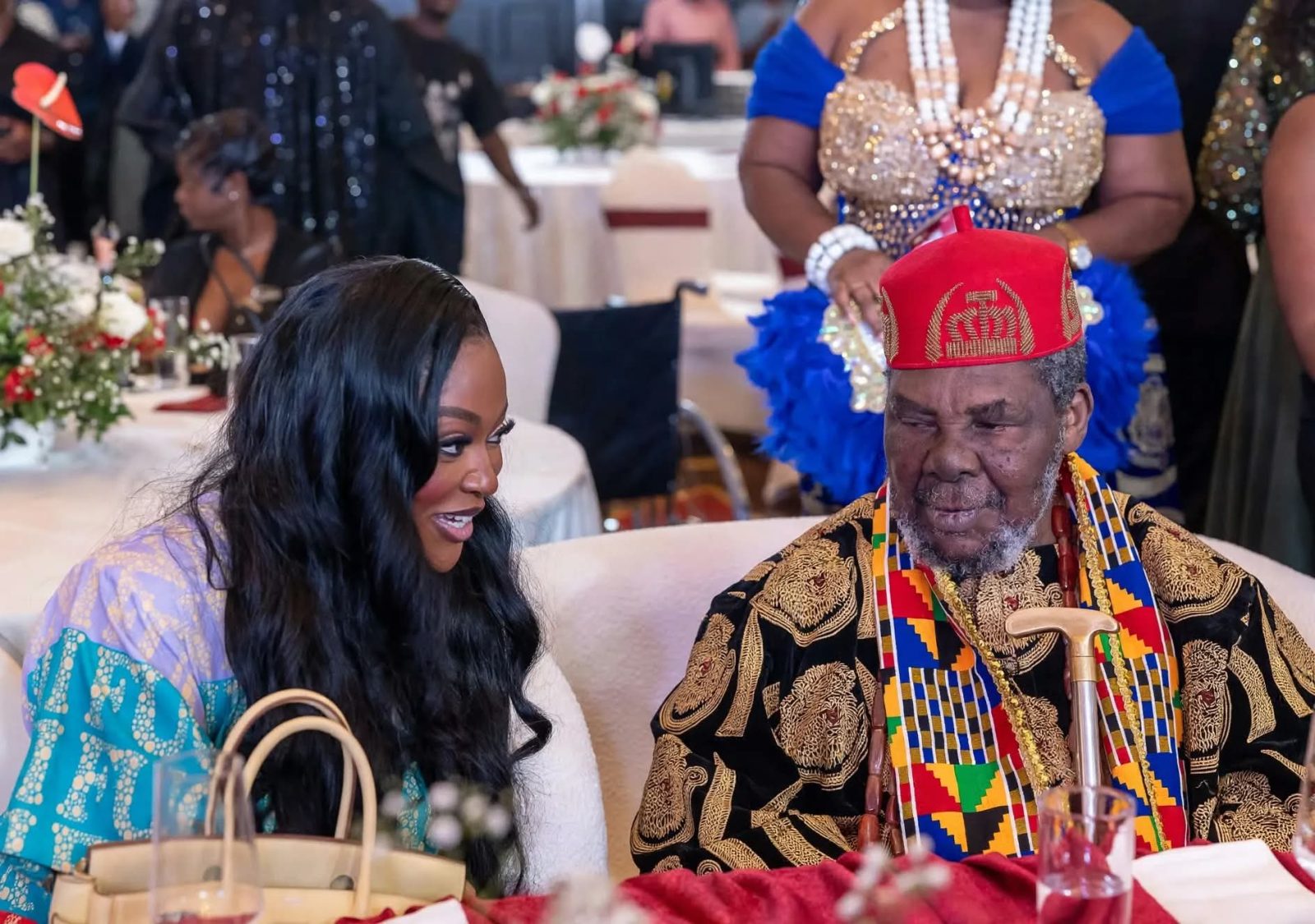 Chief Pete Edochie (right, in red cap) chatting with Jackie Appiah at the event table.