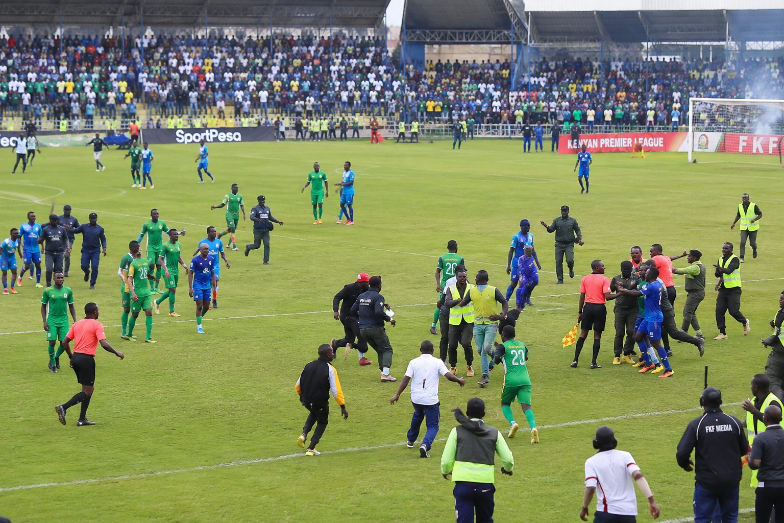 A wide stadium photo showing players and match officials during the chaos